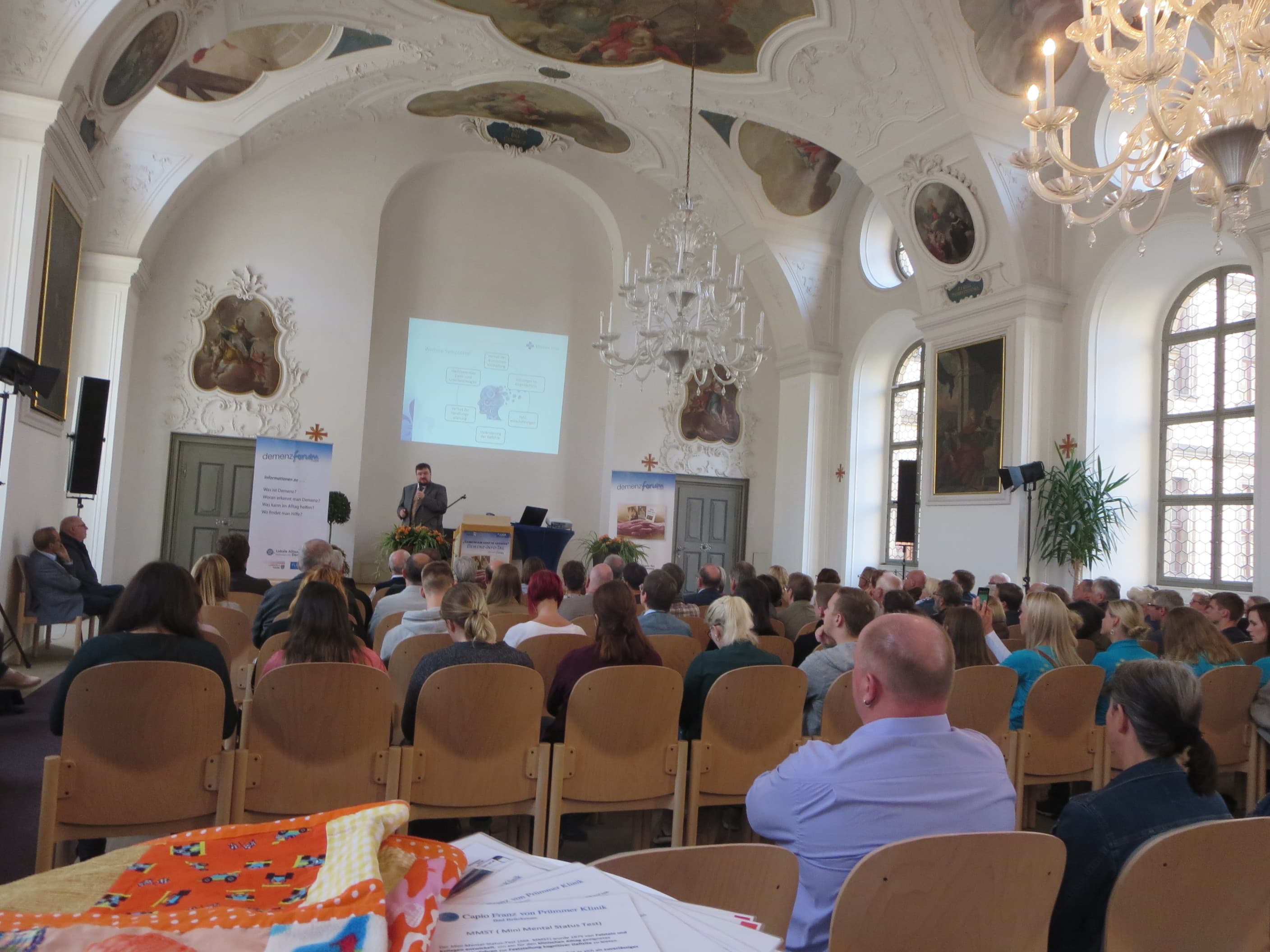 Herr Dr. Kießling in der Aula der Dalbergschule vor Publikum